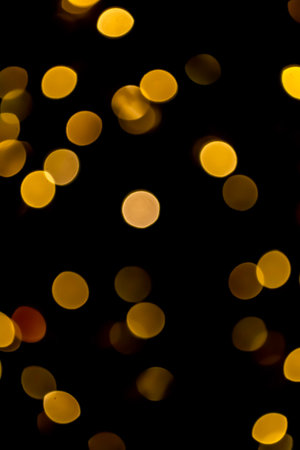 Yellow circles on a black background. Golden bokeh. Gold highlights on black. Yellow mugs in the dark.の写真素材