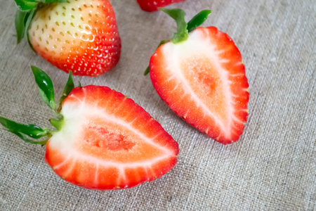 A strawberry cut in half with a green tail. Bright strawberries on a gray table. Strawberry heart.の写真素材