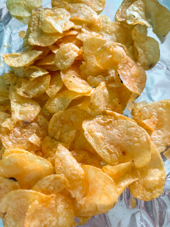 Lots of chips. Potato chips on foil. Junk food is chips.の写真素材