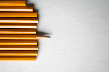 Pencils on a white sheet. Uniqueness in abstraction. One pencil out of many is sharpened. One pencil is allocated.の写真素材