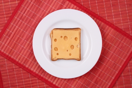Sandwich with one slice of cheese on a white plateの写真素材