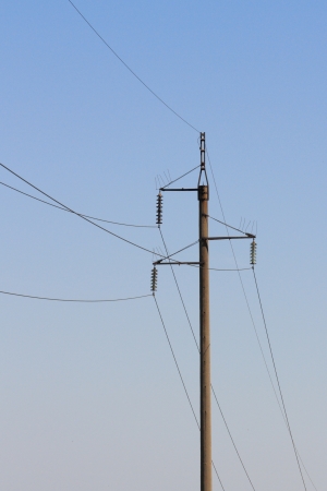 A pillar of support of high-power lines against the blue skyの写真素材