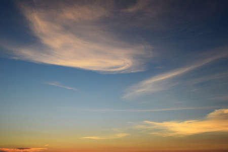 Yellow sunset against blue sky and white wispy cloudsの写真素材