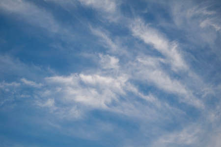 wispy white clouds against a blue skyの写真素材