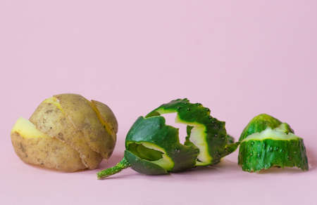 cucumber and potato peels on pink background as a symbol of recycling circulate economyの写真素材