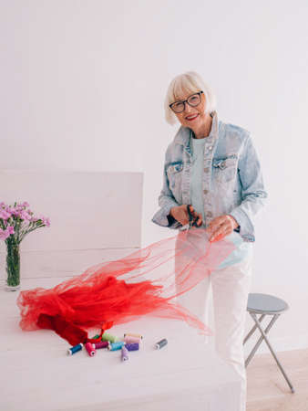 senior pensioner cheerful stylish woman clothes designer in denim jacket at work. Handmade, fashion,...