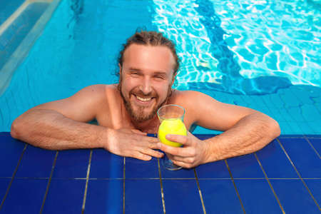 smiling cheerful caucasian european adult young man with dreadlocks and beard with cocktail near...