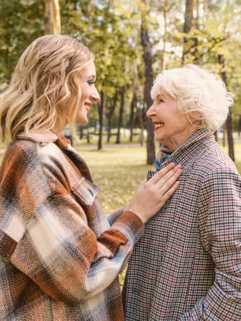senior woman with young daughter walking outdoor in autumn park. Family, generation, care, love,...