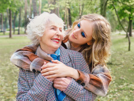 senior woman with young daughter walking outdoor in spring. Family, generation, care, love, vaccination conceptの写真素材