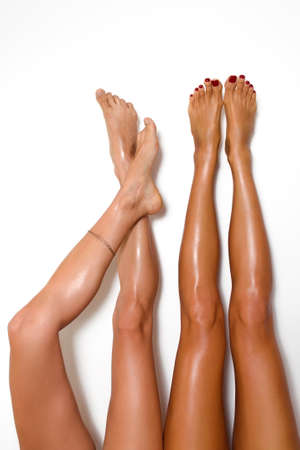 two beautiful pairs of smooth woman's legs after laser hair removal on the white background