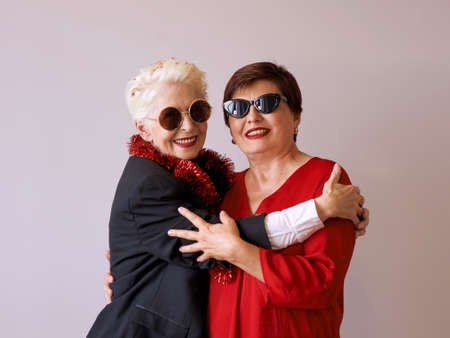 Two beautiful stylish mature senior women in sunglasses hugging. Fun, party, style, celebration conceptの写真素材