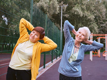 two mature women doing sport exercises in the park. healthy lifestyle conceptの写真素材