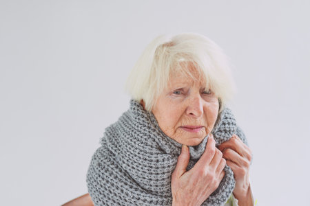 senior ill woman in scarf freezing cold at home. Health care, crisis, oldness conceptの写真素材