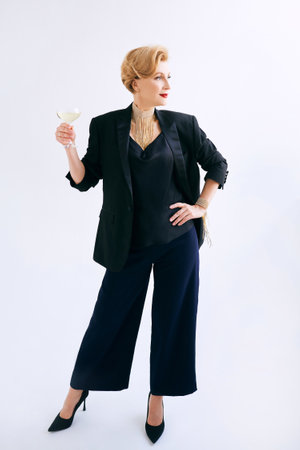 mature stylish elegant woman in tuxedo with glass of sparkling wine. Party, celebration, anti age...