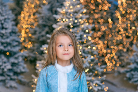cute Caucasian blonde girl walking winter christmas forest with lights. New year, fairy tale conceptの写真素材