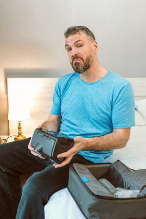 curious man with chronic breathing issues surprised by using CPAP machine sitting on the bed in...