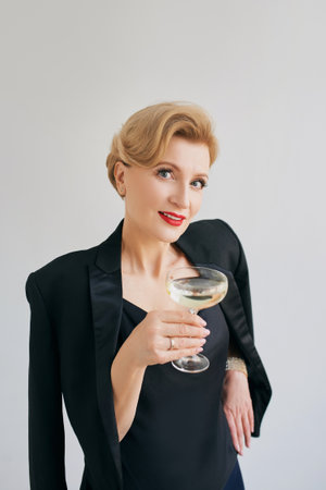mature stylish elegant woman in tuxedo with glass of sparkling wine. Party, celebration, anti age conceptの写真素材