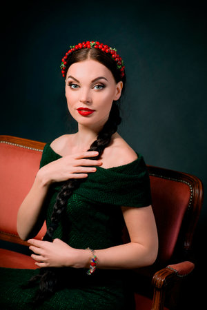 portrait of smiling young beautiful brunette with red wreath and braid on dark background