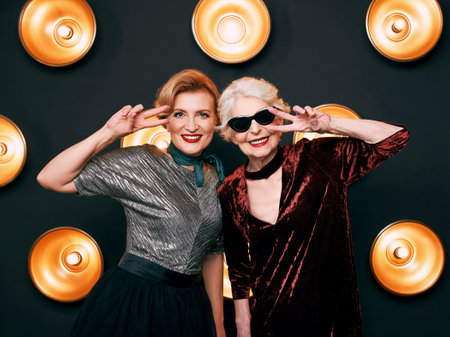 Smiling senior women in sunglasses looking at camera while standing against black background