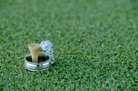 Wedding rings and a golf tee on the greenの写真素材