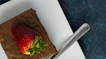 brownie with strawberry on plate on textured background