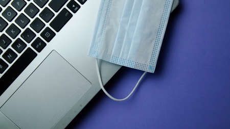biosafety element white mask accompanied by technological objects on a unicolor background
