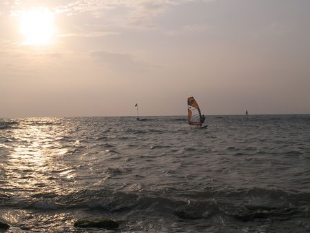 A windsurfing in front of the setting sunの写真素材