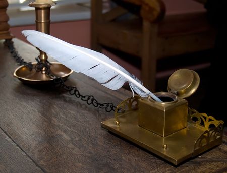 ancient inkwell and feather standing on the old oak tableの写真素材