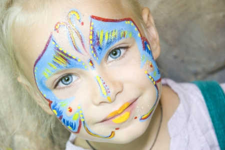 Beautiful girl with blue eyes with painted butterfly on her face