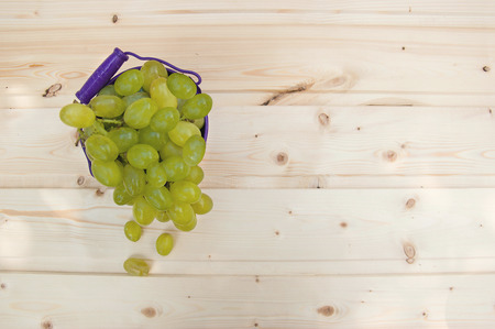 Grapes in a bucket on wooden backgroundの写真素材