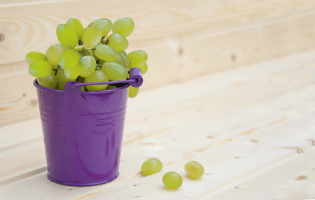 Grapes in a bucket on wooden backgroundの写真素材