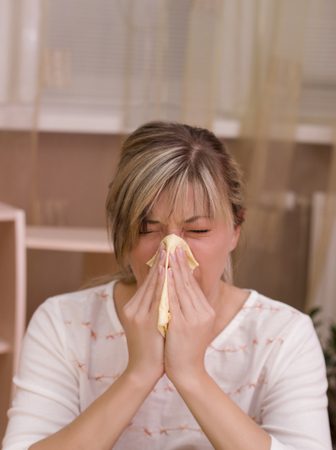 Infected woman blowing his nose in tissue paperの写真素材
