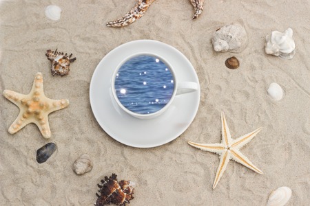 coffee and starfishes on a sandy beach background