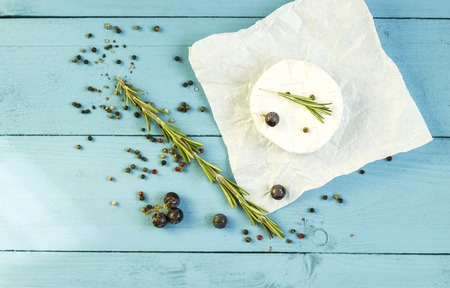 Round camembert cheese mold with rosemary on the wooden boardの写真素材