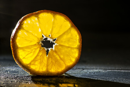 tangerine slice on wooden background back lightedの写真素材