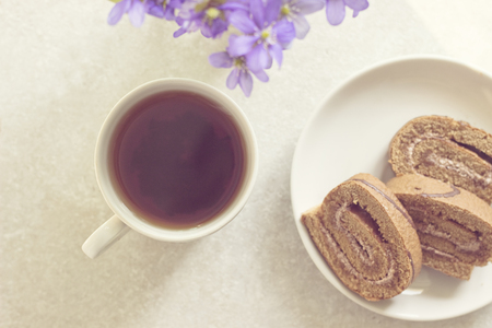 Delicious breakfast - biscuit roll with tea on a background of sunny violets.の写真素材