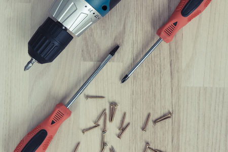 Carpenter screwing the crew with cordless screwdriver into wooden board.の写真素材