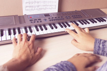 Woman teaching little girl to play the synthesizerの写真素材