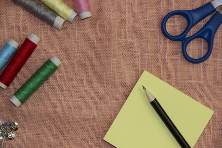 Sewing kit: multi-colored thread, thimble, scissors on a linen clothの写真素材