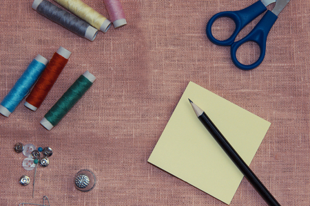 Sewing kit: multi-colored thread, thimble, scissors on a linen clothの写真素材