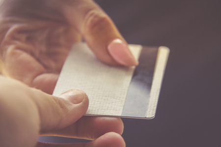 Closeup shot of a woman passing a payment credit card to the seller. Girl holding a credit card