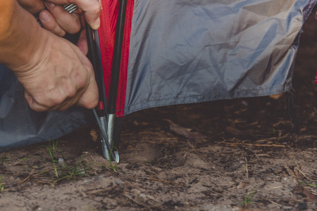 Young man tourist backpacker set up a tent on camping trip. Image of camping and travel concept.の写真素材