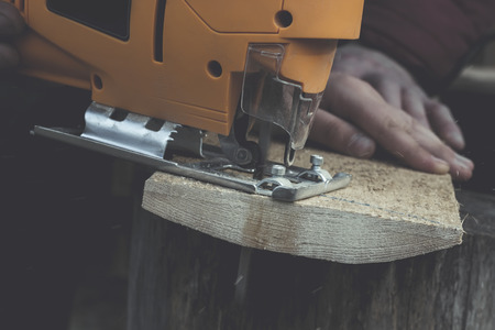 Man cuts wood products, using electric jigsaws outdoors. Close-upの写真素材