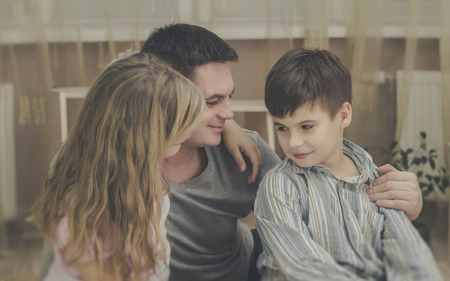 Beautiful portrait of a father with his to kids at home.の写真素材
