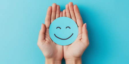 hands with blue paper smiley face on blue backgroundの素材