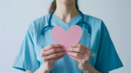 nurse holding a pink paper heart in her handsの素材