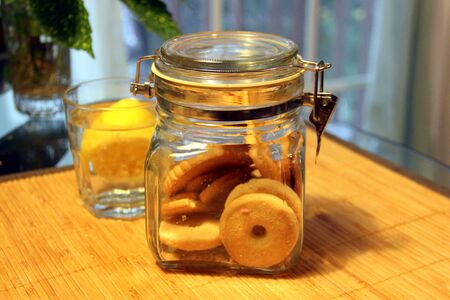 Cookie jar and a lemon in a glass of water in the background on a tableの写真素材
