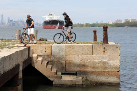 Teenage cyclists on the old stone pier by the Narrows at Fort Wadsworth, Staten Island, NY, USA - May 17, 2020のeditorial素材