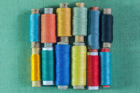 Multicolored threads in reels lie in a row
