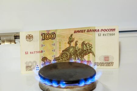 A fire is burning from a gas burner, in the background one hundred rubles. Gas price concept.の写真素材